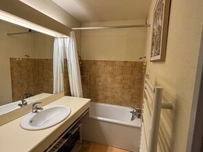 Een badkamer met een wastafel, spiegel, bad en douchegordijn.