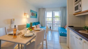 A compact kitchen with a dining area, a microwave, a sink, and a window with curtains. - Cozy studio in Cap Esterel with balcony and pool access (Saint-Raphaël)