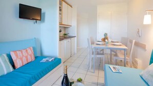 A compact room with a bed, a small dining table, and a kitchenette. - Cozy studio in Cap Esterel with balcony and pool access (Saint-Raphaël)