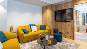 A modern living room with a yellow sofa, a coffee table, and a TV mounted on a wooden wall.