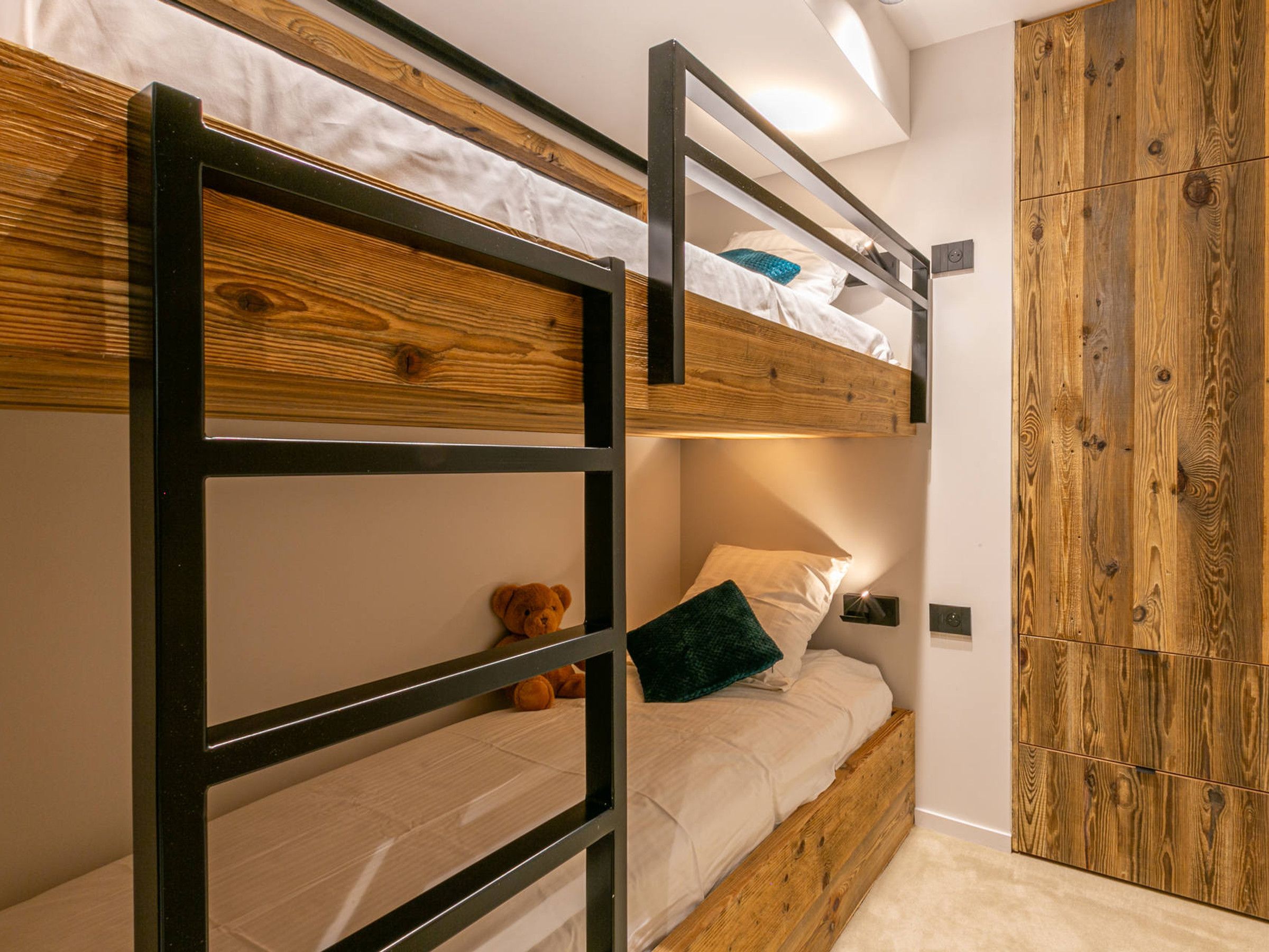 Un letto a castello con testiera in legno e un comodino con lampada.