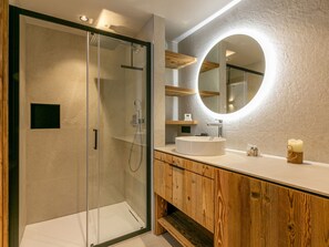 A modern bathroom with a glass-enclosed shower, a wooden vanity, and a round mirror. - Ski-in/Ski-out Apartment with WiFi, Garage, and Balcony in Val-d'Isère (Val-d'Isère)