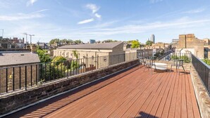 A rooftop terrace with a wooden deck, stone walls, and a view of the cityscape. - Luxury Apartment London Eye Westminister (London)