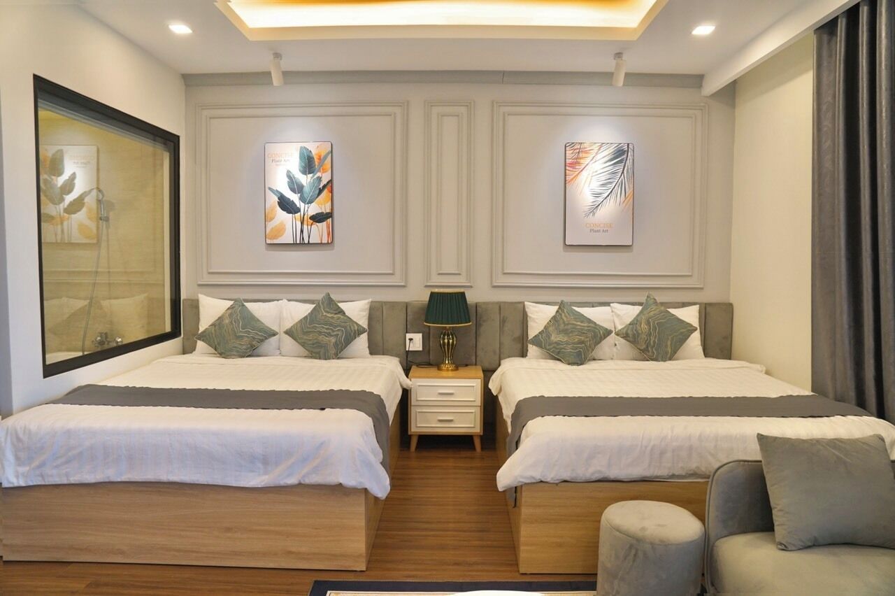 Una habitación de hotel moderna con dos camas, un pequeño espacio de descanso y obras de arte en las paredes.