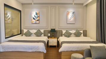 Una habitación de hotel moderna con dos camas, un pequeño espacio de descanso y obras de arte en las paredes.