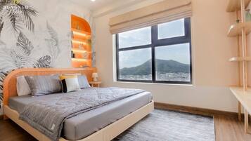 A modern bedroom with a large bed, a city view, a bookshelf, and a tropical mural.