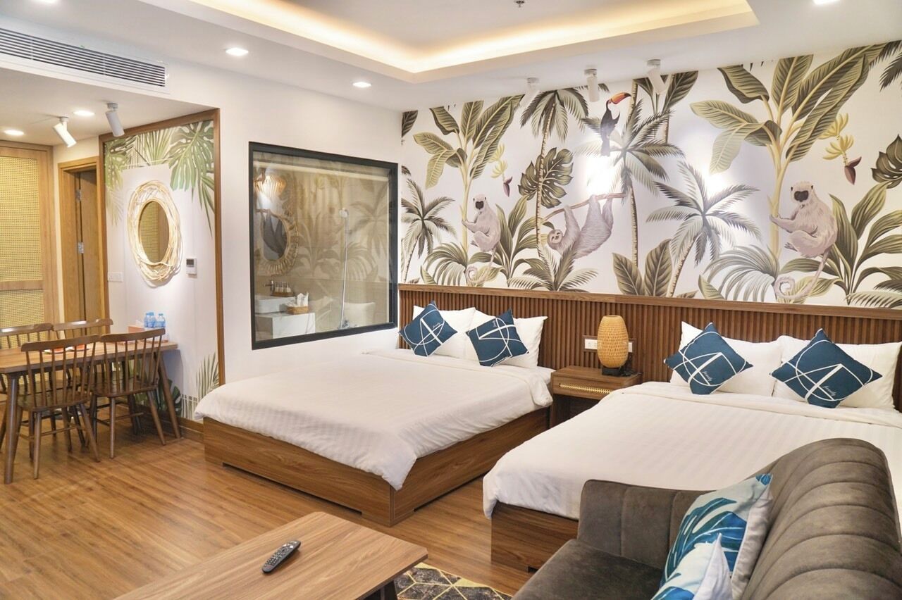 A hotel room with two beds, a wooden dining table, and a large mirror.