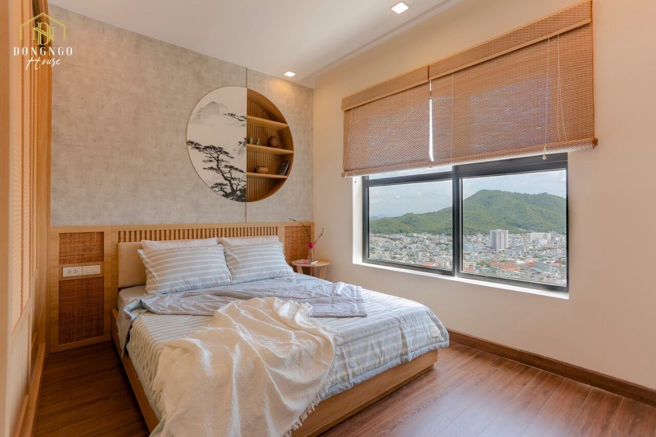 A bedroom with a bed, a wall-mounted shelf, a window with a view of a cityscape, and a ceiling light.
