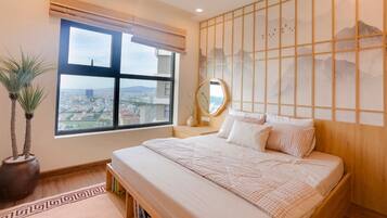 A bedroom with a large window, a bed, a bedside table, a mirror, and a decorative wall panel.