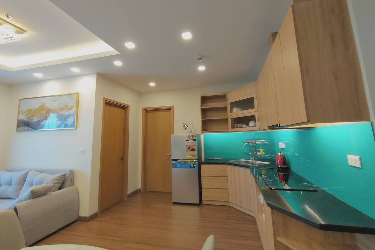 A modern kitchen with wooden cabinets, a teal backsplash, and a built-in refrigerator.