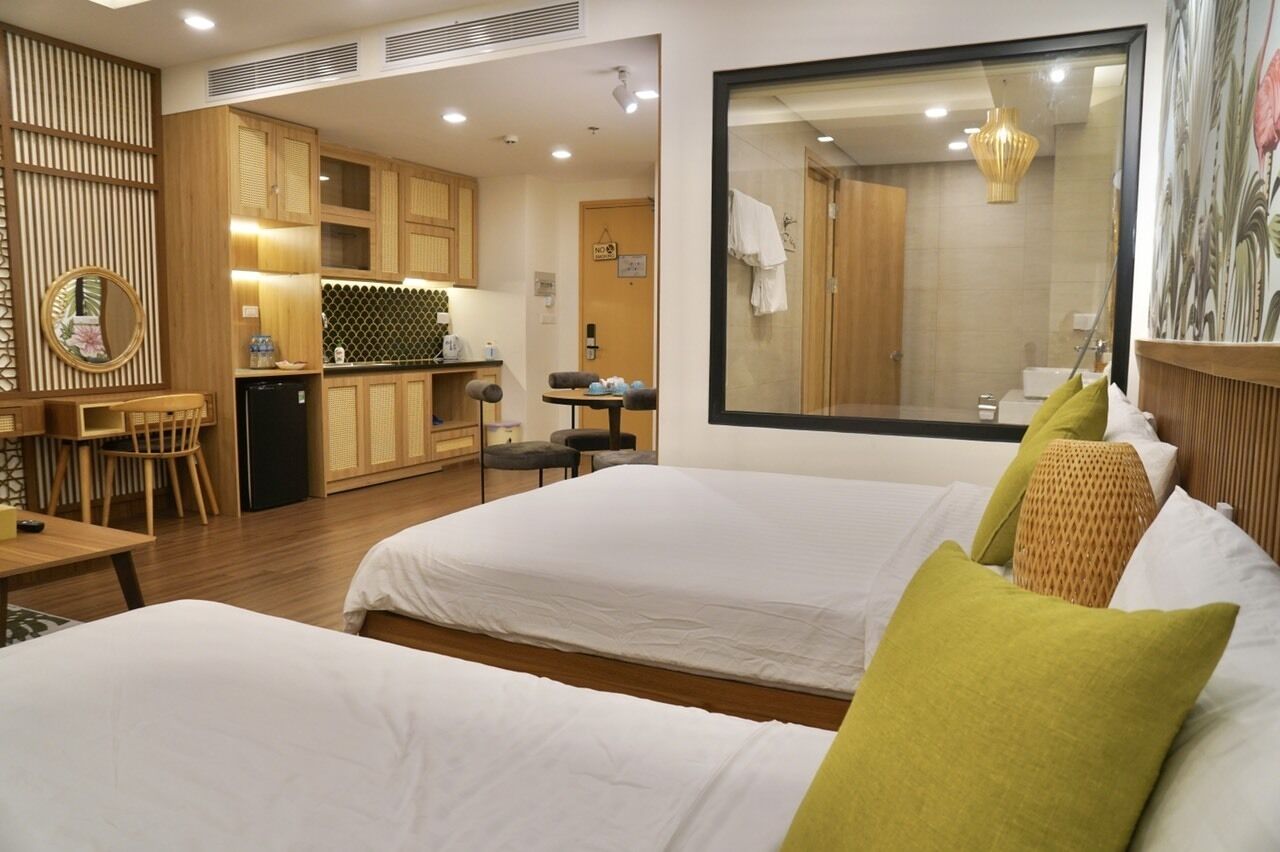 A hotel room with two beds, a dining area, and a kitchen.