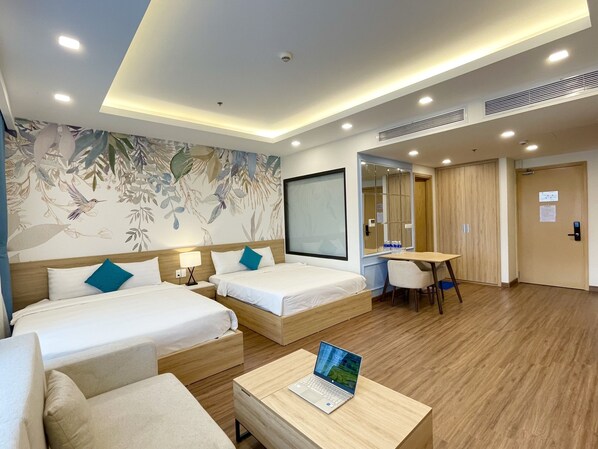 A hotel room with two beds, a desk, a laptop, and a mirror. - FLC Sea Tower - Quynhon Homes (Quy Nhon Nam)