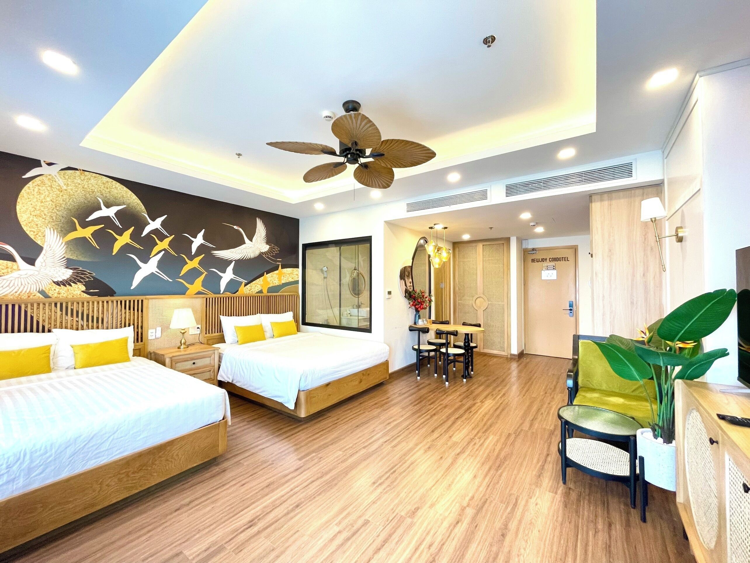 Quarto de hotel com duas camas, área de refeições, chuveiro e um espelho grande.