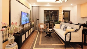 A modern living room with a sofa, coffee table, and a TV mounted on the wall. - FLC Sea Tower - Quynhon Homes (Quy Nhon Nam)