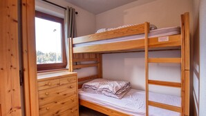 A bunk bed room with a wooden dresser and a window. - 6-Person Apartment at Foot of Slopes, Balcony, Equipped Kitchen (Morillon 1100)