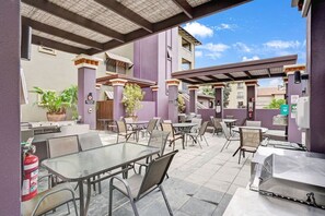 Une terrasse extérieure avec des tables et des chaises, un barbecue et un extincteur.