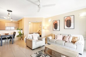 A modern living room with a sofa, a coffee table, and a dining area with chairs and a table.