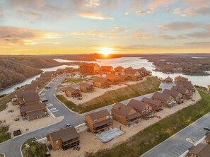 A resort with multiple buildings, a parking area, and a river in the background.