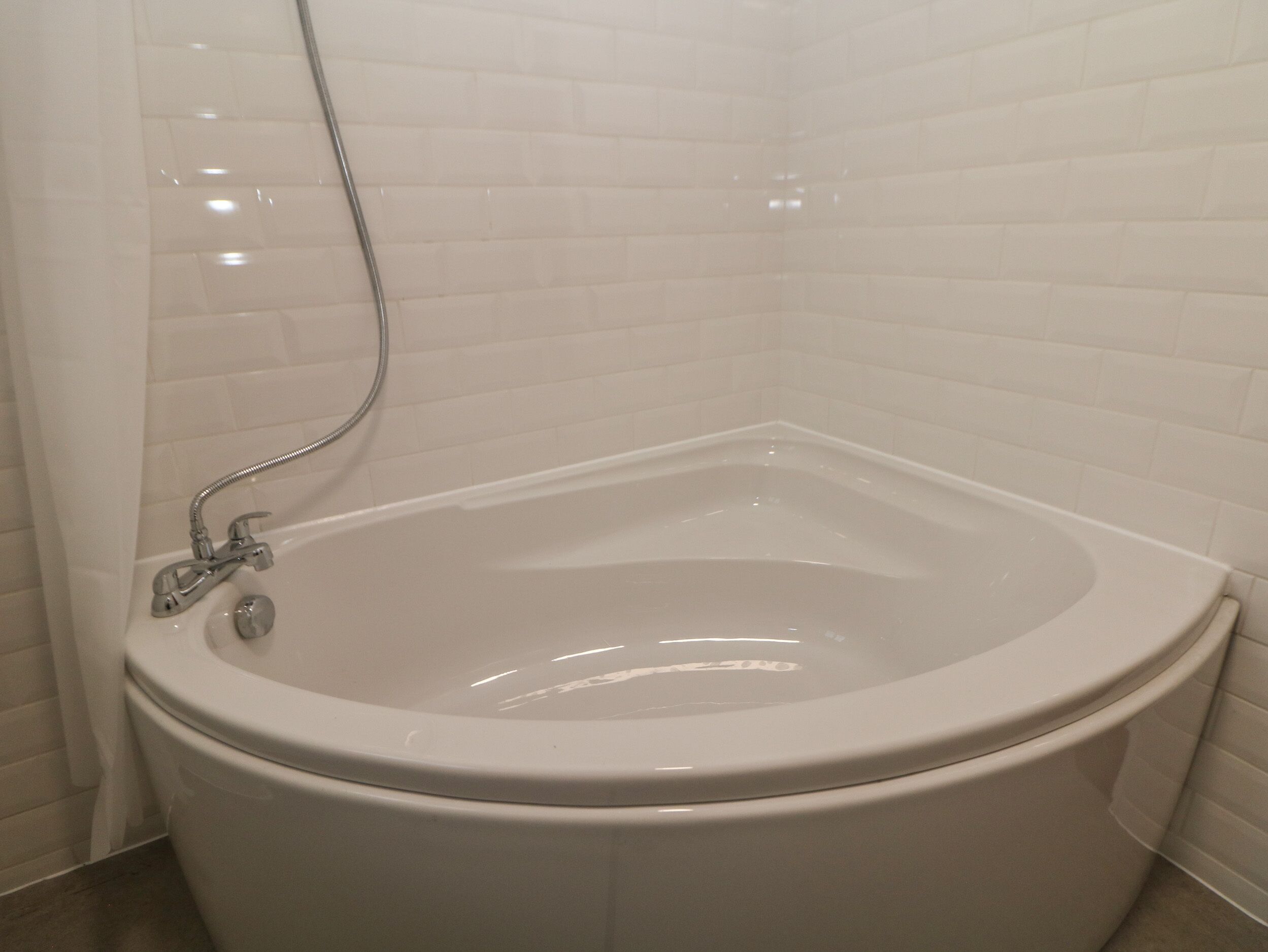 A bathroom with a white bathtub, a shower head, and a toilet.