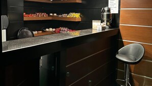 Una zona de bar con estantes que exhiben aperitivos y una máquina de café.
