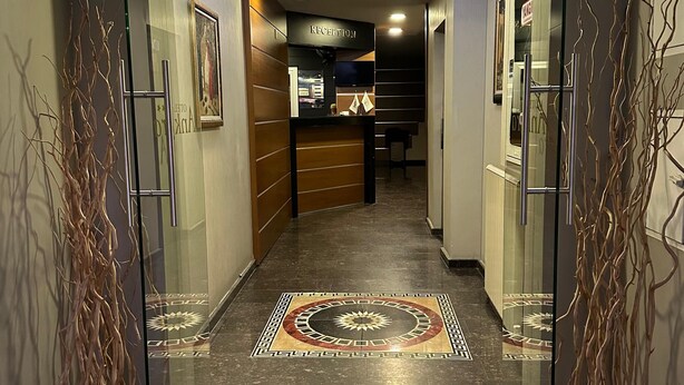 Zona de recepción con mostrador, piso estampado y paredes de vidrio con ramas decorativas.