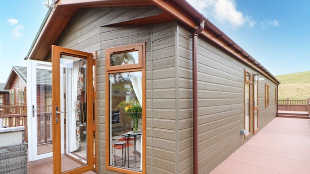A wooden cabin with a glass door and windows, a deck, and a view of a garden. - 10 Poppy Lodge (Richmond)