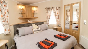 A cozy bedroom with a bed, a bedside table, a mirror, and a wardrobe. - 10 Poppy Lodge (Richmond)