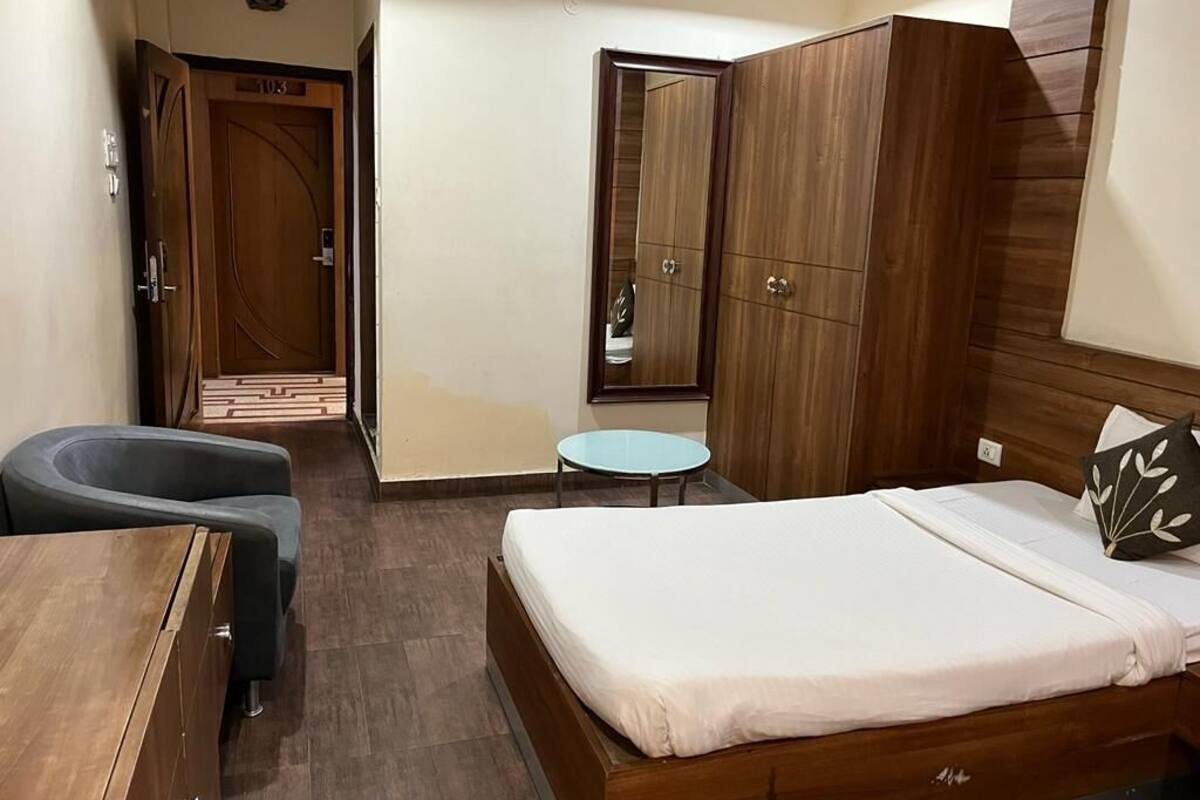 A bedroom with a bed, a desk, a chair, a small round table, and a wardrobe.