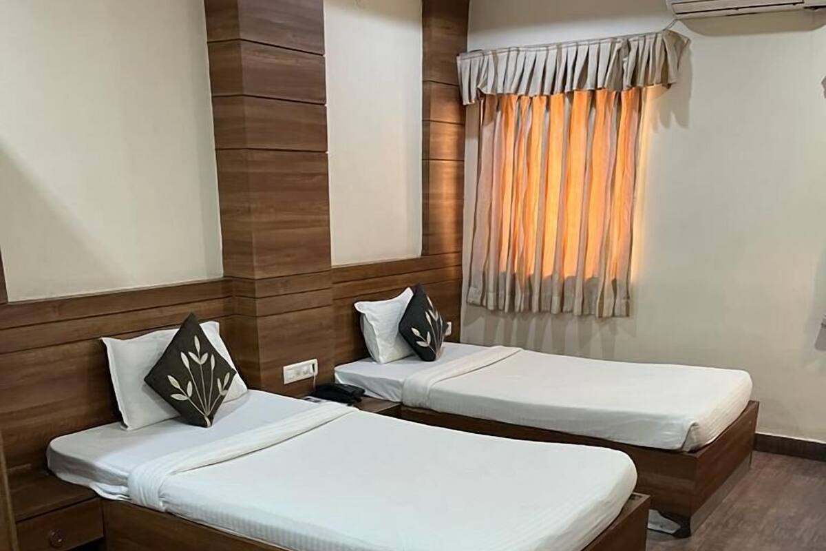 A hotel room with two single beds, a small round table, and a sofa.