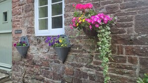 Un edificio de piedra con una ventana y macetas con flores.