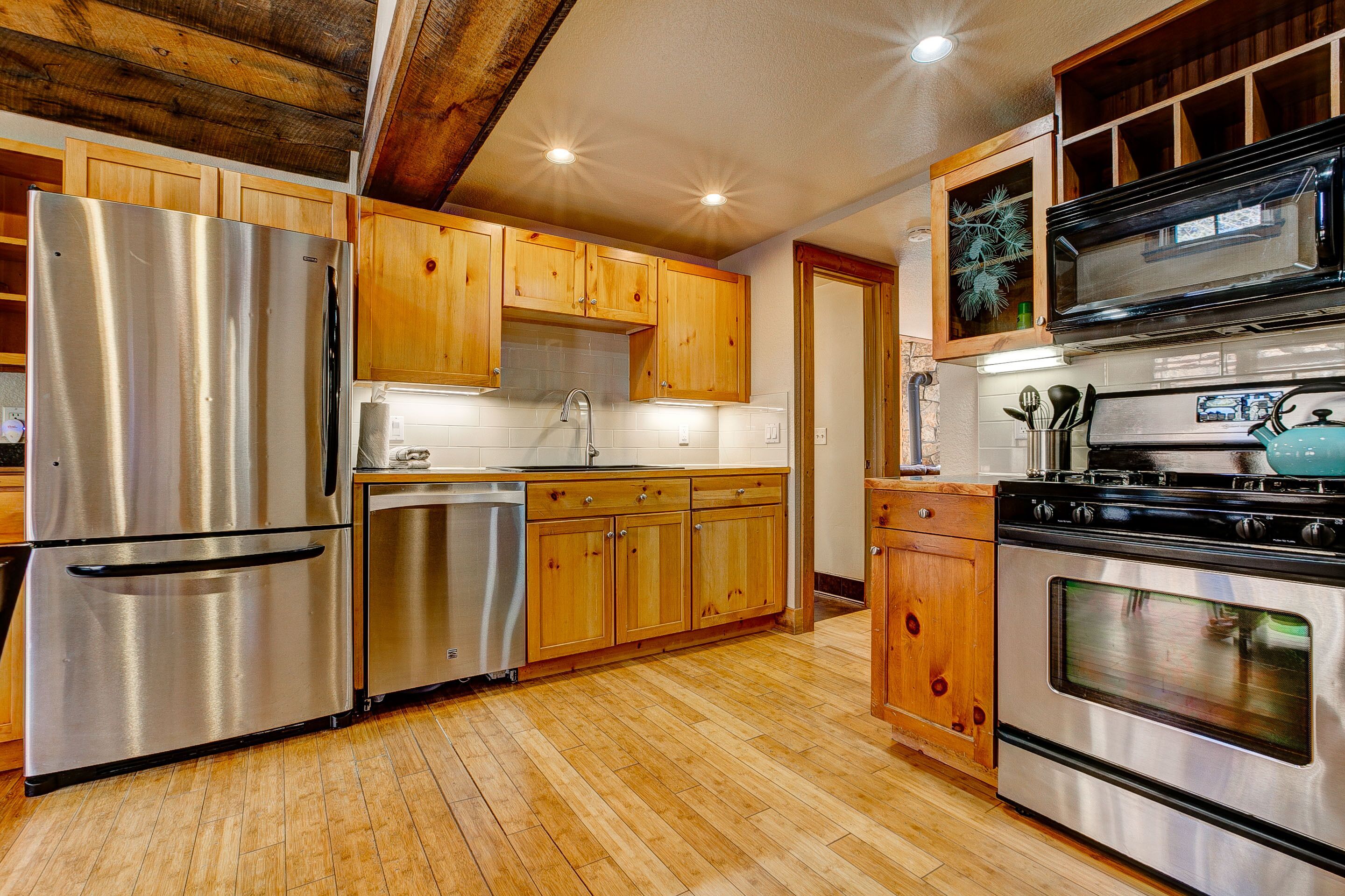 A kitchen with wooden cabinets, stainless steel appliances, and a tiled backsplash.