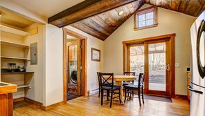 A dining area with a wooden table and chairs, a kitchen with a refrigerator, and a laundry room with a washing machine. - Evergreen View - A Modern Mountain Retreat (Estes Park)