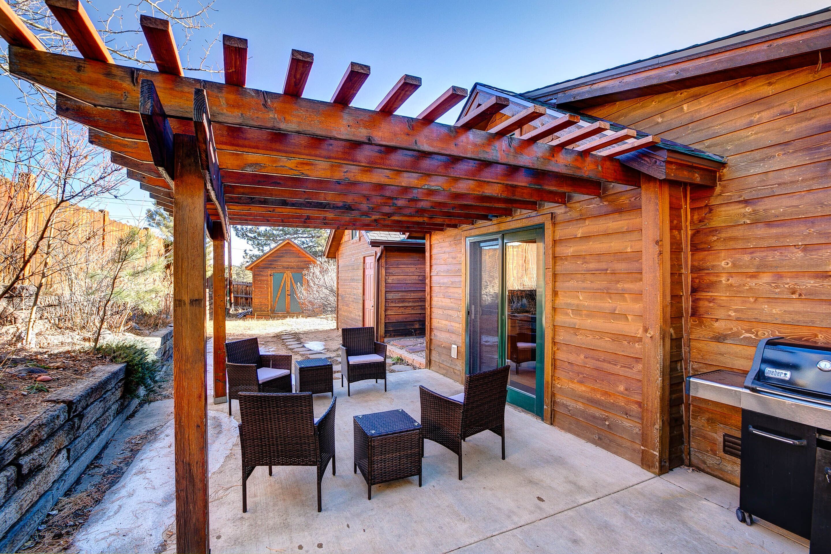 A wooden cabin with a covered patio area featuring outdoor furniture and a grill.