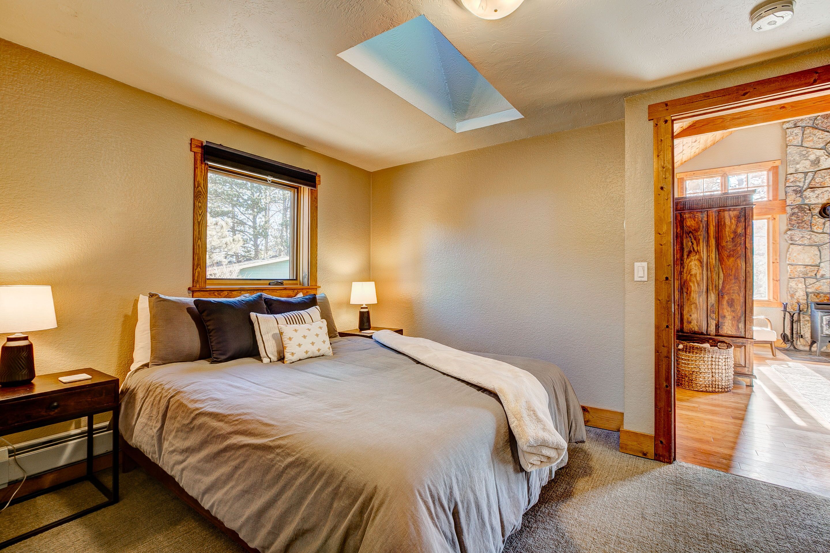 A bedroom with a large bed, two bedside tables, a window, and a skylight.