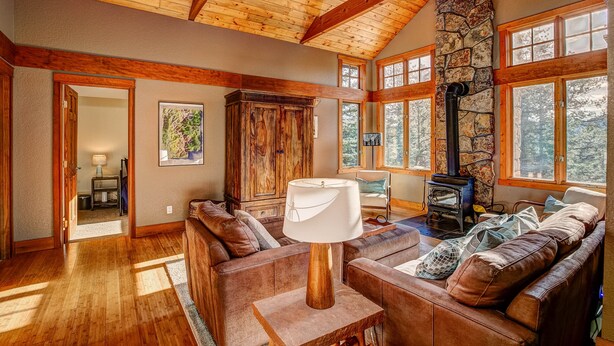 A cozy living room with a stone fireplace, wooden beams, and large windows. - Evergreen View - A Modern Mountain Retreat (Estes Park)