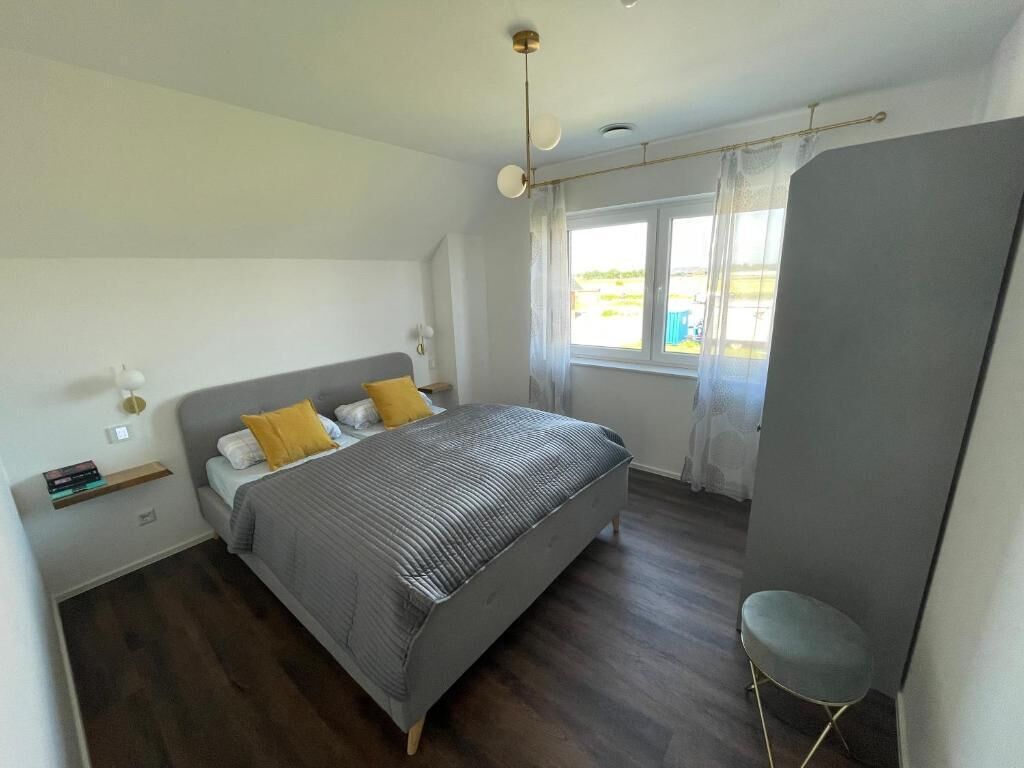 Une chambre à coucher avec un lit, une table de chevet et une fenêtre avec des rideaux.
