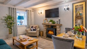 Una sala de estar acogedora con chimenea, televisor y comedor con una mesa dispuesta para dos.