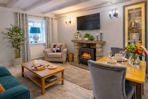 A cozy living room with a fireplace, a television, and a dining area with a table set for two.