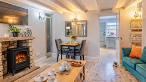 Una sala de estar acogedora con chimenea de piedra, un comedor con mesa dispuesta para el té, y un sofá color turquesa.