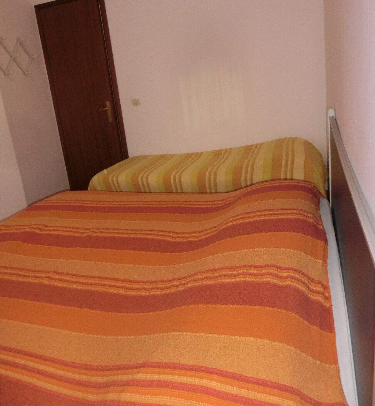 Een bed met gestreepte beddengoed en een houten deur op de achtergrond.