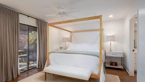 Ein Bett mit Baldachin und Holzrahmen, eine Bank am Fußende und ein Nachttisch mit Lampe.