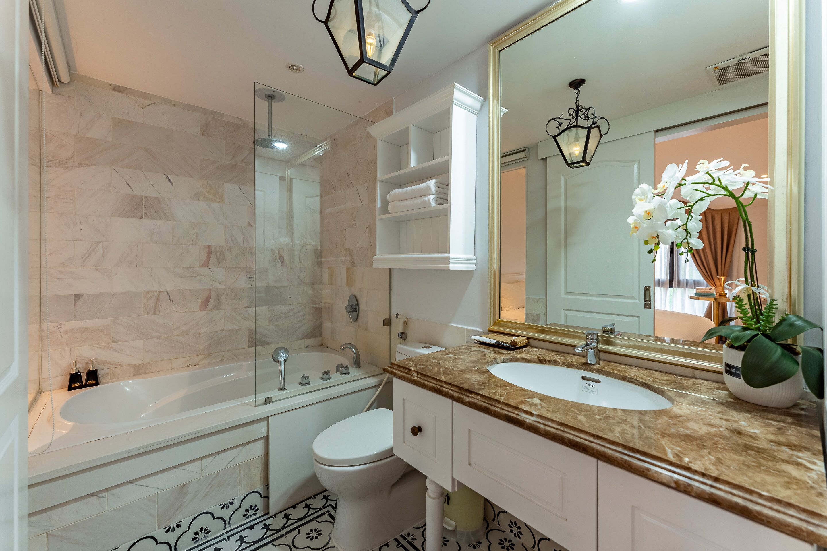 Un baño moderno con ducha envuelta en vidrio, una bañera blanca, un inodoro y un lavamanos con lavabo y espejo.