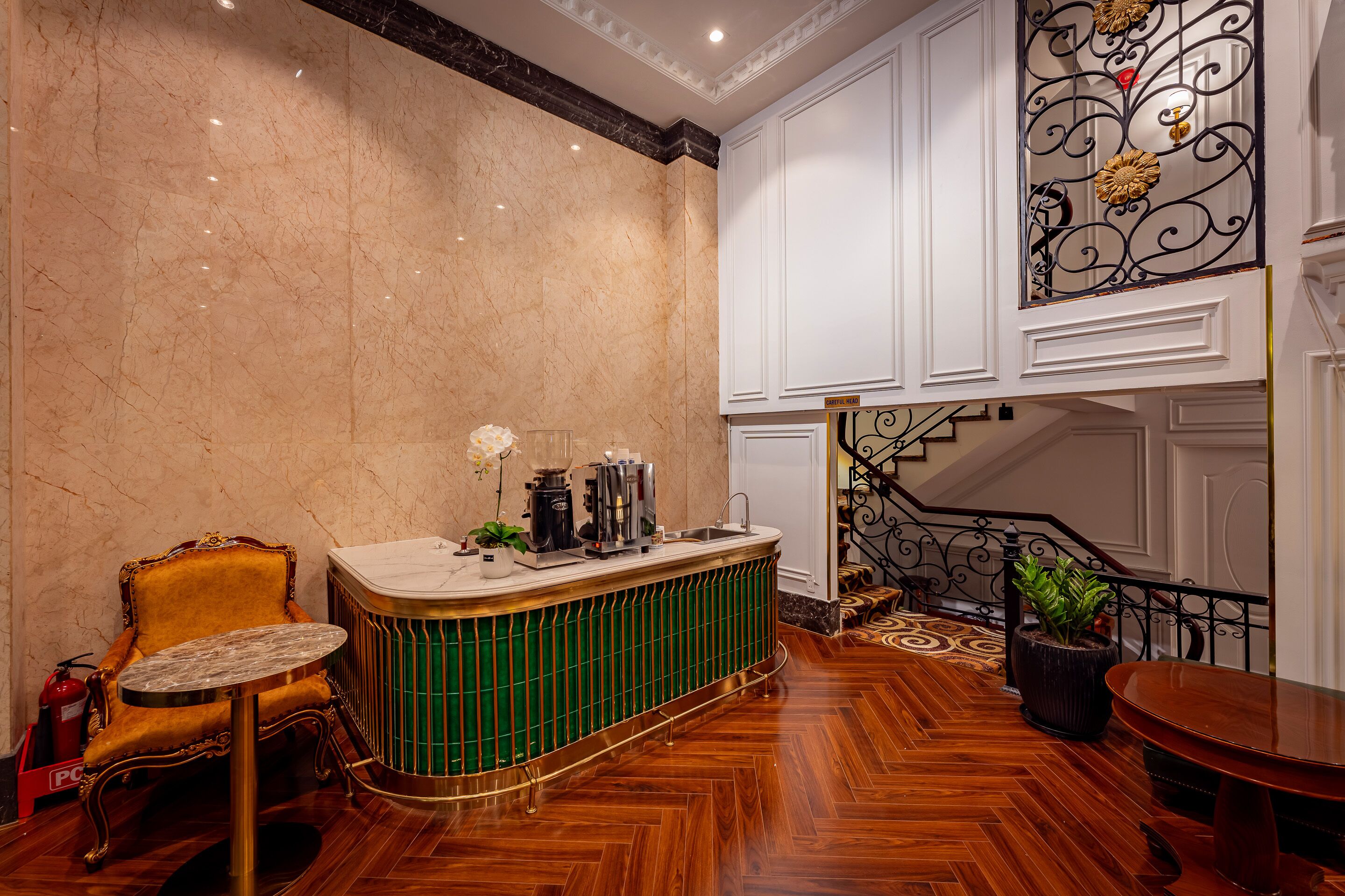 A lobby with a marble wall, a green bar counter, a yellow chair, and a staircase.