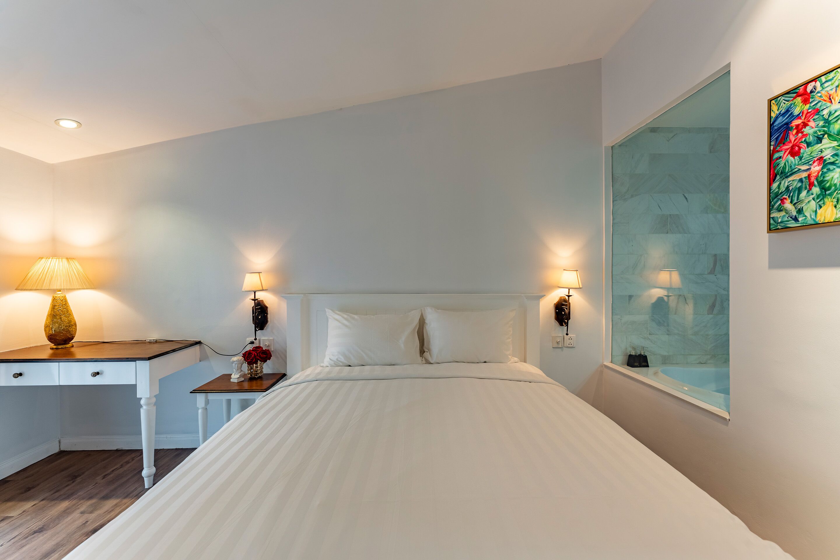 Quarto com cama, luminárias de cabeceira, escrivaninha e janela com vista.