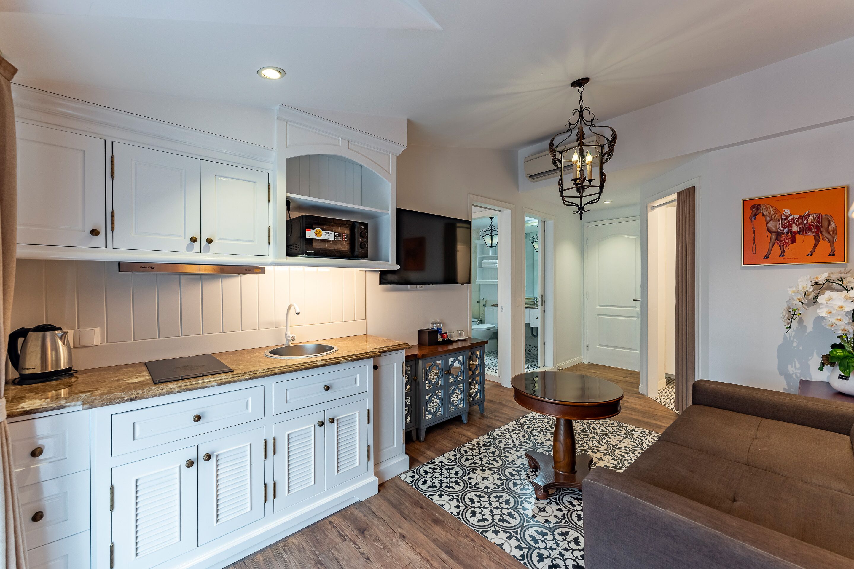 A modern kitchen with white cabinetry, a wooden countertop, and a built-in microwave.
