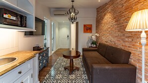 A modern kitchen with a built-in oven, a dining area with a round table, and a brick wall.