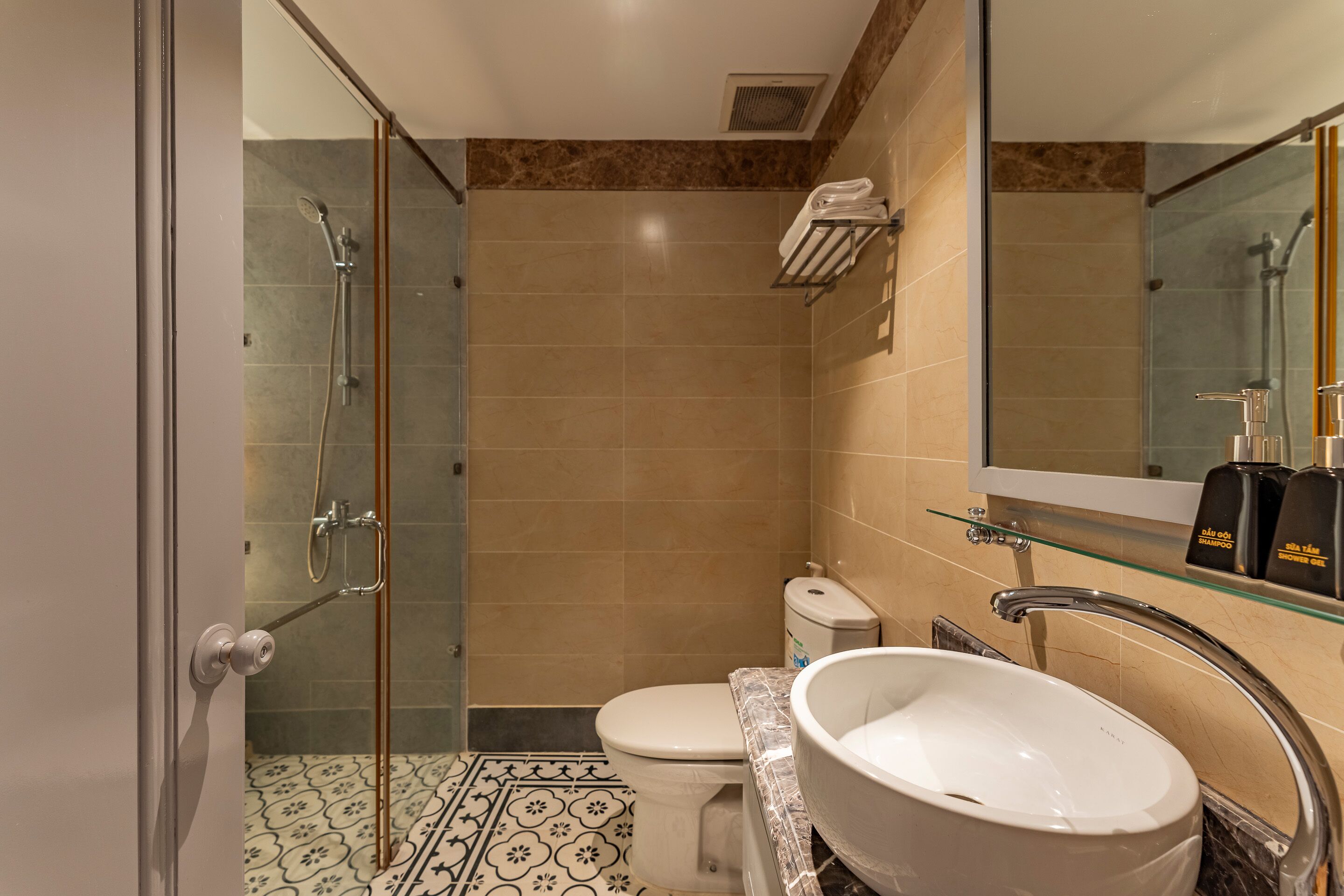 A modern bathroom with a glass shower enclosure, a white toilet, and a large white sink with a marble countertop.