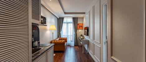 A narrow hallway with a sofa, a desk, and a television.