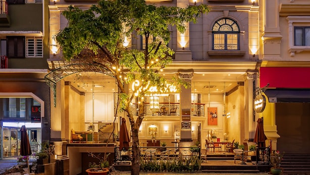 A multi-story hotel with a classic architectural style, featuring arched windows and a balcony.