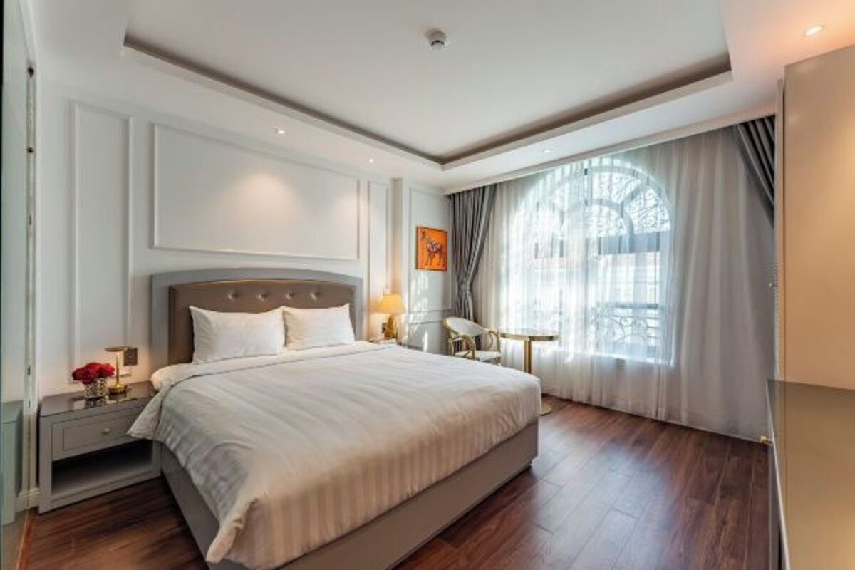 Un dormitorio espacioso con una cama grande, una mesita de noche y una ventana con cortinas.